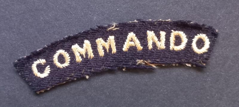 A superb - albeit regrettably single - early white on black embroided commando shoulder title