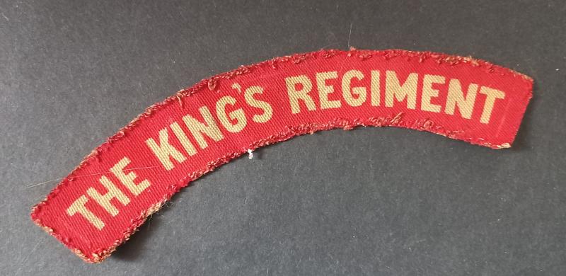 A nice and issued (regrettably missing its black backing) The King's Regiment printed shoulder title