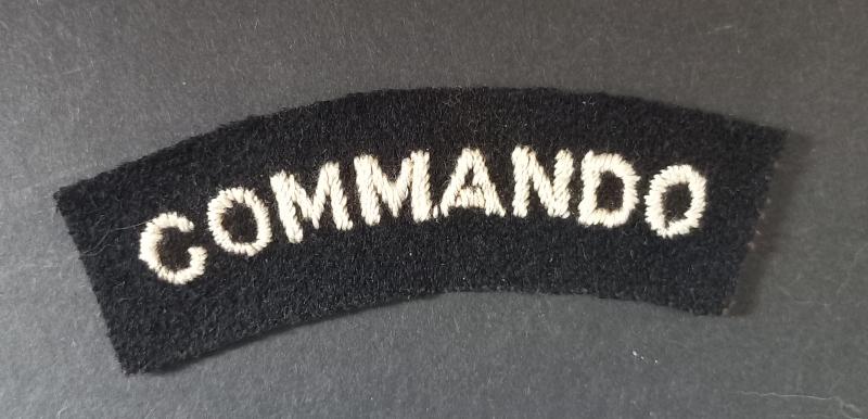 A superb - albeit regrettably single - mid war period white on black embroided commando shoulder title